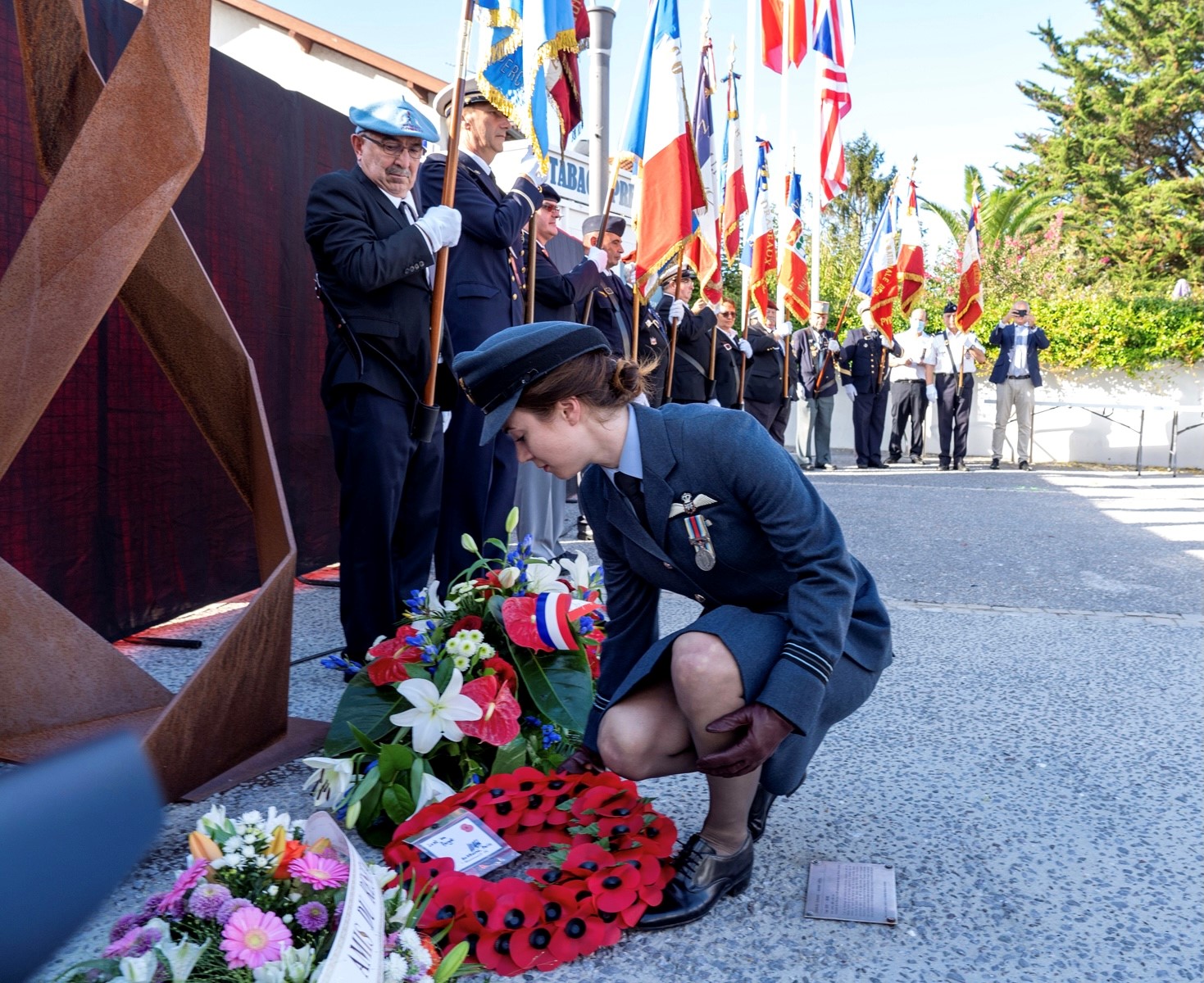 Personnel lays a wreath with flag bearers in the background.